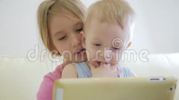 可爱的弟弟妹妹使用数字平板电脑微笑着看上去很开心兄弟姐妹玩得开心视频的预览图