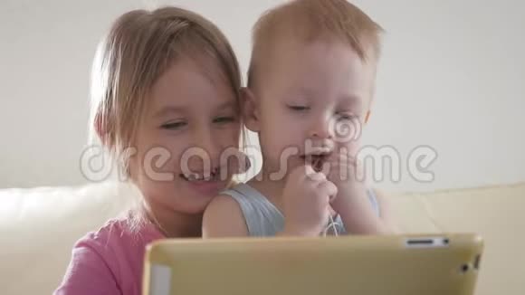 可爱的弟弟妹妹使用数字平板电脑微笑着看上去很开心兄弟姐妹玩得开心视频的预览图