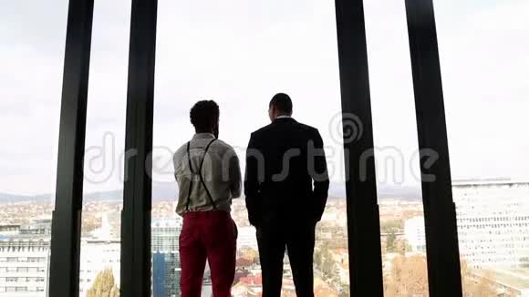 两个商人透过窗户望着城市说话视频的预览图