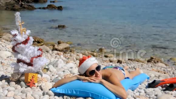 年轻女子带着圣诞树在沙滩上放松视频的预览图