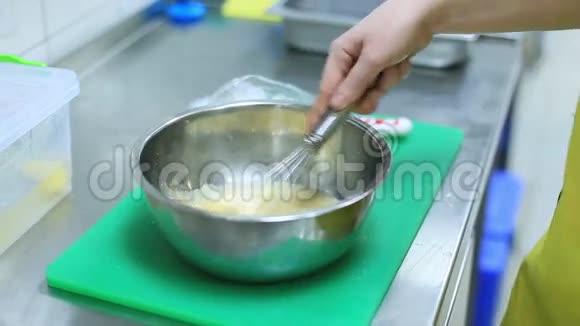 女性手在金属搅拌碗中搅拌面糊视频的预览图