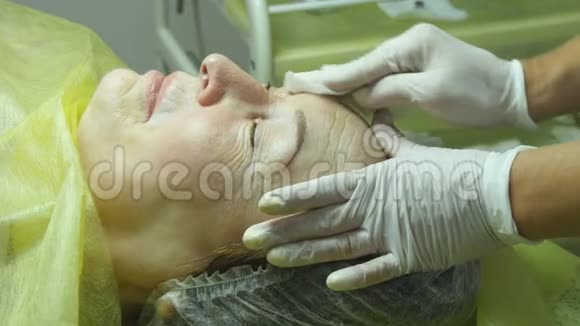 美容师的手正在为手术或手术后的清洁准备皮肤老女人撒谎然后视频的预览图