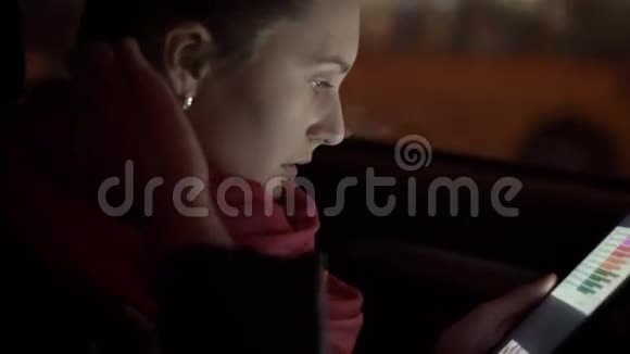 年轻女孩坐在车里晚上用平板电脑4K视频的预览图