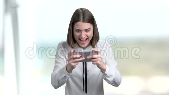 年轻有趣的女人在智能手机上玩游戏视频的预览图