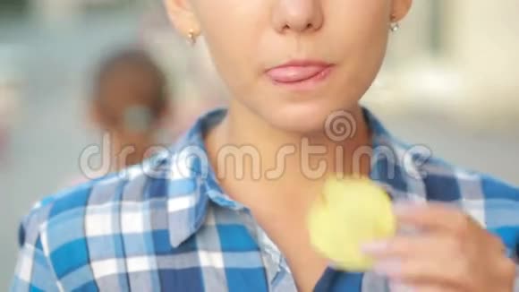 女孩在街上在户外吃薯片漂亮的年轻女人吃薯片视频的预览图