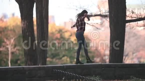 秋天公园的快乐女人快乐而兴奋的年轻女子在阳光明媚的秋天公园里玩着扔黄叶的乐趣视频的预览图