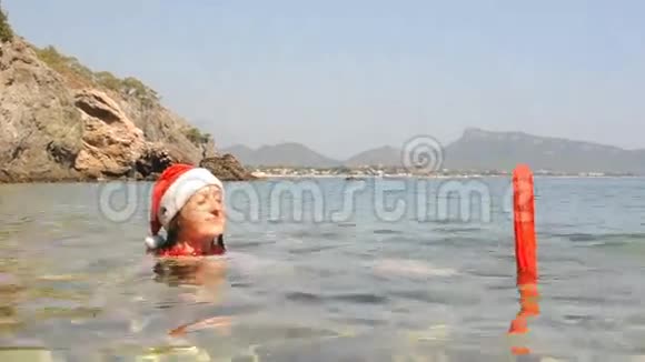 美丽的年轻女子戴着圣诞帽在海里游泳视频的预览图