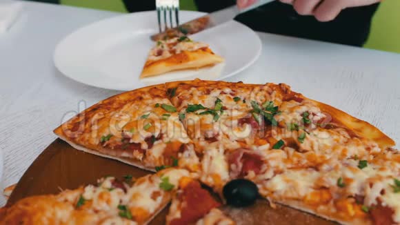 男人在时尚的白色背景下吃着美味的新鲜出炉的披萨里面有奶酪玉米西红柿肉和草药视频的预览图