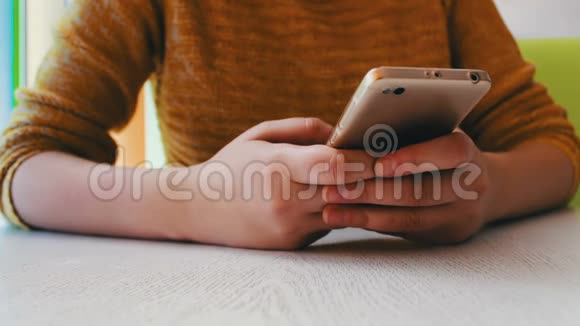 穿着黄色毛衣的女孩坐在咖啡馆里有东西在智能手机上打字视频的预览图