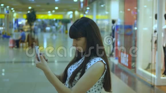 年轻女子在购物中心玩口袋妖怪在室内玩使用智能手机女孩玩流行的智能手机游戏视频的预览图
