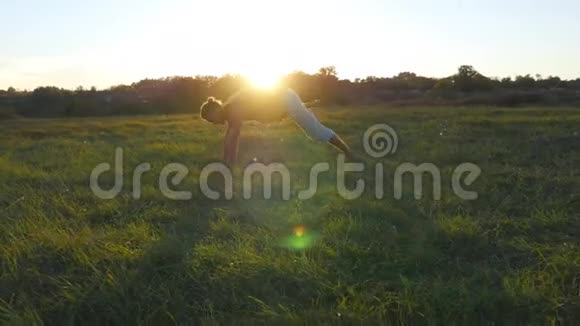 年轻人在草地上练习瑜伽动作和姿势在大自然中站着瑜伽姿势的运动员视频的预览图
