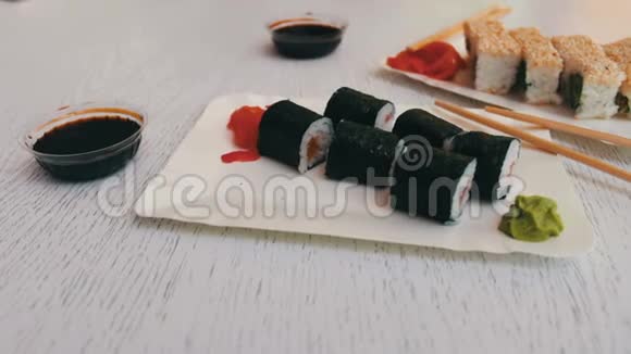 日本料理寿司有三文鱼粉姜青芥末和白色盘子上的酱油视频的预览图