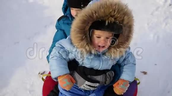 一个快乐的孩子骑着车在雪山上的雪管里微笑视频的预览图