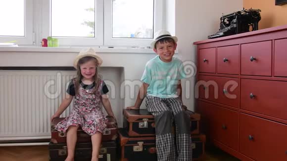 可爱的小女孩和男孩坐在老式手提箱上等待开始度假小女孩穿花裙子视频的预览图