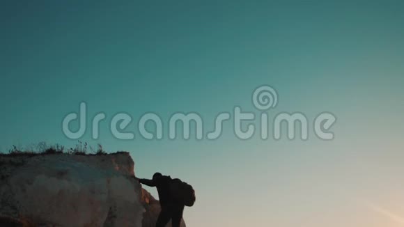 一位游客在日落探险时爬上山顶的剪影生活方式的剪影视频的预览图