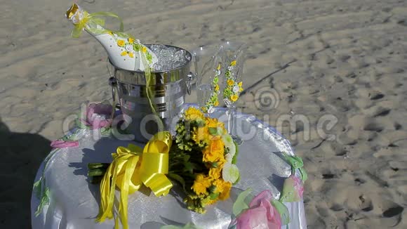 冰桶中的香槟瓶两个玻璃杯和海滩上的婚礼装饰视频的预览图
