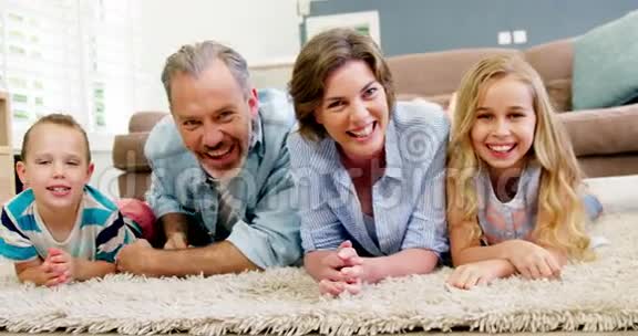 幸福的家庭躺在客厅的地毯上视频的预览图