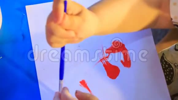 孩子的手在纸上用刷子涂红线视频的预览图