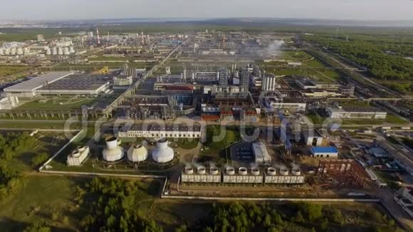 一个巨大的炼油厂有管道和蒸馏的综合体在一个绿色的田野被森林包围空中景观视频的预览图