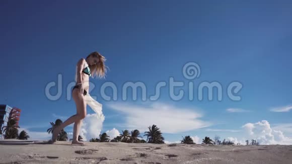 女孩沙滩大海风在你的头发穿比基尼的女孩在沙滩上散步视频的预览图