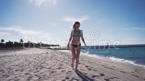 女孩沙滩大海风在你的头发穿比基尼的女孩在沙滩上散步视频的预览图
