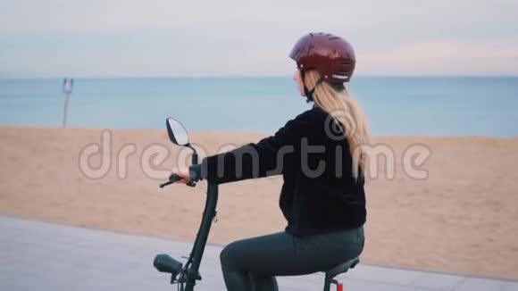 漂亮的金发女人在海边驾驶电动自行车视频的预览图