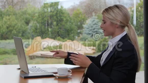 微笑的女人在电话里说话在笔记本电脑上工作视频的预览图
