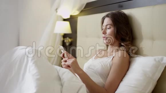 女人在床上用智能手机视频的预览图