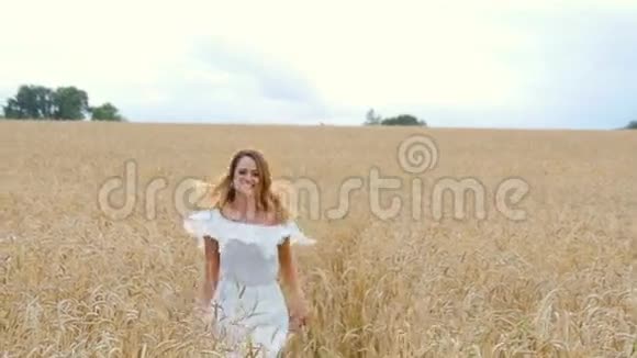 穿着白色连衣裙在田野上奔跑的年轻女子视频的预览图