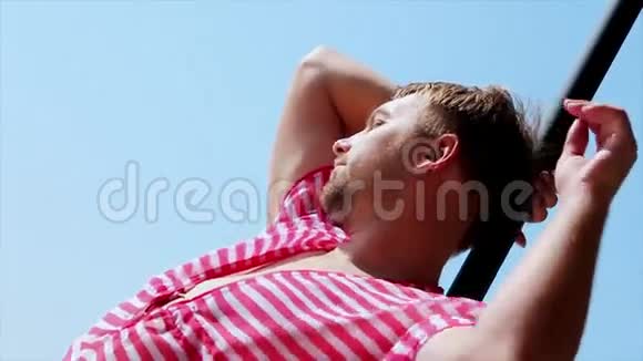 穿着粉色外套的人在海滩伞上对着镜头摆姿势风夏日阳光明媚蓝天视频的预览图