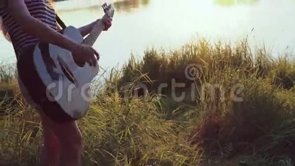 那个女孩在傍晚池塘附近弹吉他4k视频的预览图