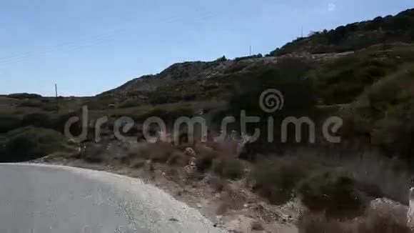 驾驶摩托车行驶在密洛斯岛蜿蜒曲折的道路上视频的预览图