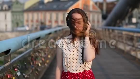 漂亮的女孩在爱锁的桥梁上用耳机听音乐视频的预览图