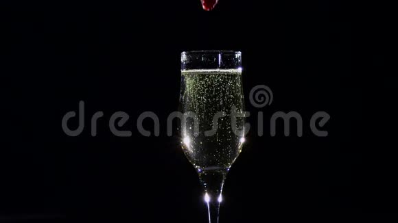 慢动作带着香槟酒倒在玻璃里的黄色草莓视频的预览图