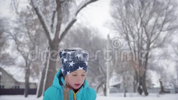 快乐的小女孩在雪地上玩雪冬天在公园散步视频的预览图