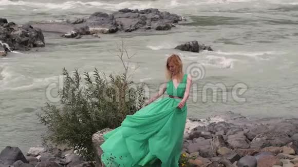 年轻的女人穿着一件长长的流动的衣服在河山的背景上给一个在绿色中盘旋的女人上色视频的预览图