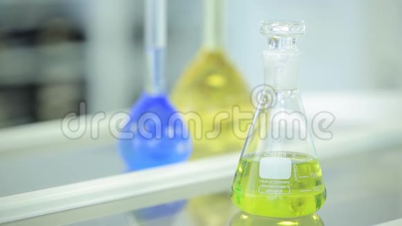 带有彩色液体和反射的实验室玻璃器皿试管和瓶装有绿色和蓝色液体视频的预览图