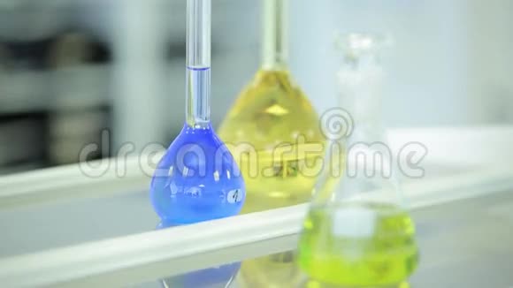 带有彩色液体和反射的实验室玻璃器皿试管和瓶装有绿色和蓝色液体视频的预览图