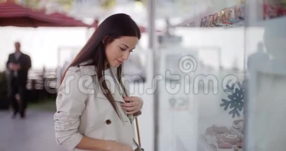 时尚的年轻女性在购物中心浏览视频的预览图