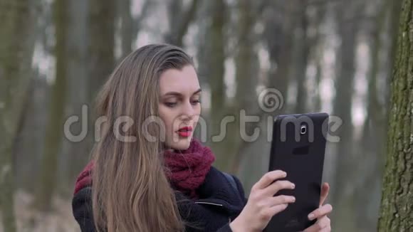 一个在森林里拿着平板电脑的女孩的肖像慢慢地视频的预览图