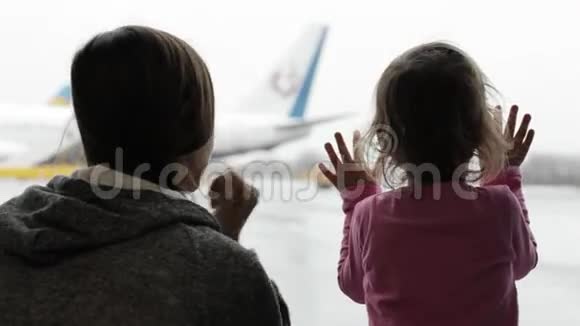 妈妈和小女儿在机场候机楼看着窗外视频的预览图
