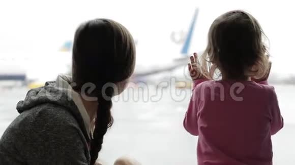 妈妈和小女儿在机场候机楼看着窗外视频的预览图