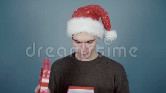 戴着圣诞帽的年轻人打开一个礼品盒鼻子上被击中视频的预览图