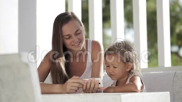 母女俩在阳台上看智能手机上的搞笑视频视频的预览图