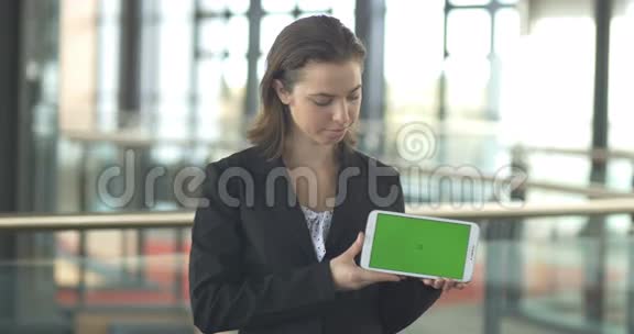 带耳机的女商人带绿色屏幕的独立平板电脑视频的预览图