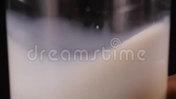 牛奶放在透明的玻璃里黑色的背景一个人拿着一杯牛奶放回桌子上视频的预览图