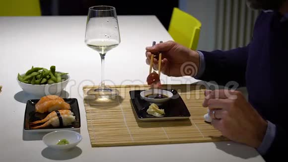 有胡子的男人在晚餐时吃寿司和喝白葡萄酒的慢动作视频视频的预览图