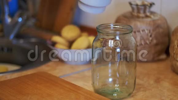 牛奶被倒入一个透明的罐子在家庭厨房的背景慢动作视频的预览图
