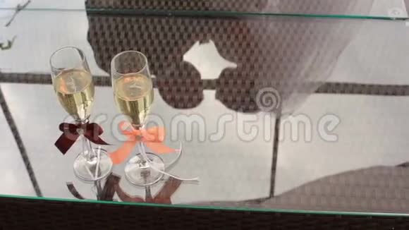 两杯香槟桌上挂着五颜六色的丝带在玻璃上反射婚礼夫妇视频的预览图