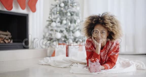 年轻的非洲女孩躺着看她的圣诞礼物视频的预览图
